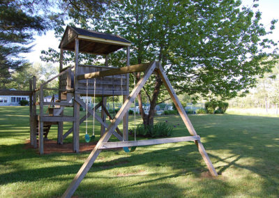 A wooden swing set in a grassy area.
