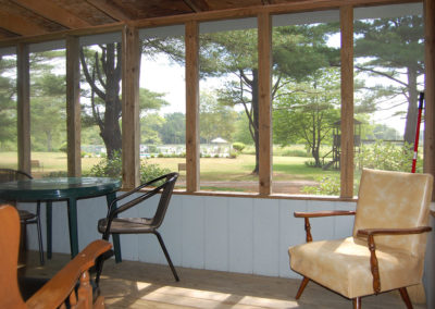 A screened porch with a table and chairs.