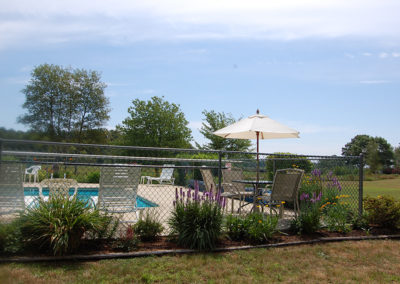 A fence with a pool and chairs.