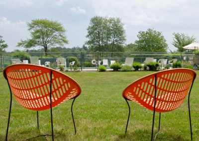 Two orange chairs in a grassy field.