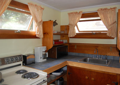 A kitchen with a stove, sink, and cabinets.