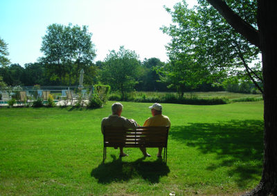 A couple sitting on a bench in a grassy area.