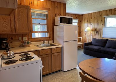 An eat-in kitchen with a fridge, dining table, sink and range.