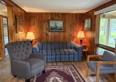 A living room in a cottage with a sofa and two chairs